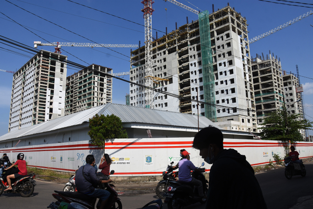 Warga melintas di dekat proyek pembangunan rumah susun sederhana sewa (rusunawa) PIK Pulo Gadung. Foto: ANTARA FOTO/Indrianto Eko Suwarso
