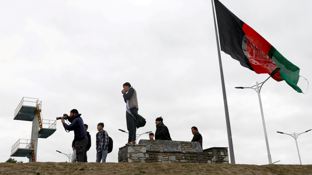 Pemuda berfoto di sebelah bendera Afghanistan di puncak bukit yang menghadap ke Kabul, Afghanistan. Foto: Mohammad Ismail/REUTERS