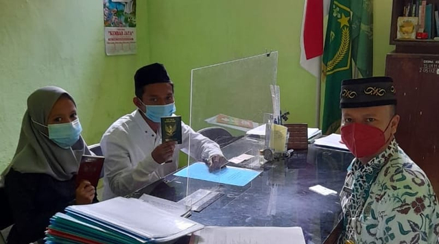Kepala KUA Tegal Timur Syamsul Arif memberikan kartu nikah fisik kepada pasangan pengantin di kantor KUA setempat, Jumat (13/8/2021) (Dok. KUA Tegal Timur)