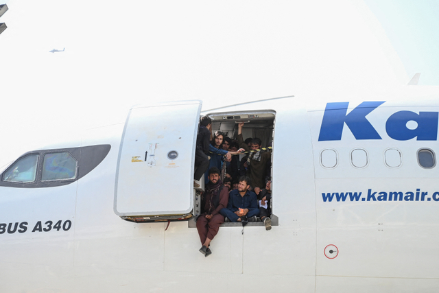 Orang-orang Afghanistan naik ke pesawat dan duduk di dekat pintu saat mereka menunggu di bandara Kabul di Kabul pada 16 Agustus 2021. Foto: WAKIL KOHSAR / AFP)