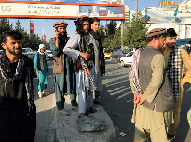 Seorang anggota Taliban (tengah) berdiri di luar Bandara Internasional Hamid Karzai di Kabul, Afghanistan, 16 Agustus 2021. Foto: REUTERS/Stringer