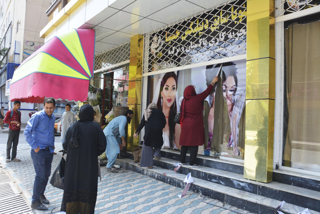 Pekerja di salon kecantikan melepas foto-foto besar wanita dari dinding di Kabul. Foto: Reuters