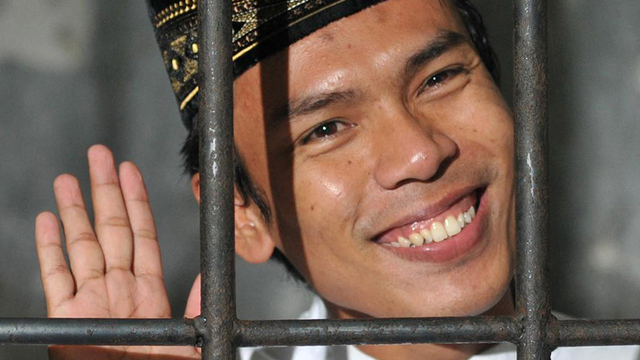 Pembunuh berantai Indonesia Verry Idham Henyansyah yang dikenal sebagai Ryan melambai di balik jeruji setelah pengadilan negeri di Depok menjatuhkan hukuman mati. Foto: Bay Ismoyo/AFP