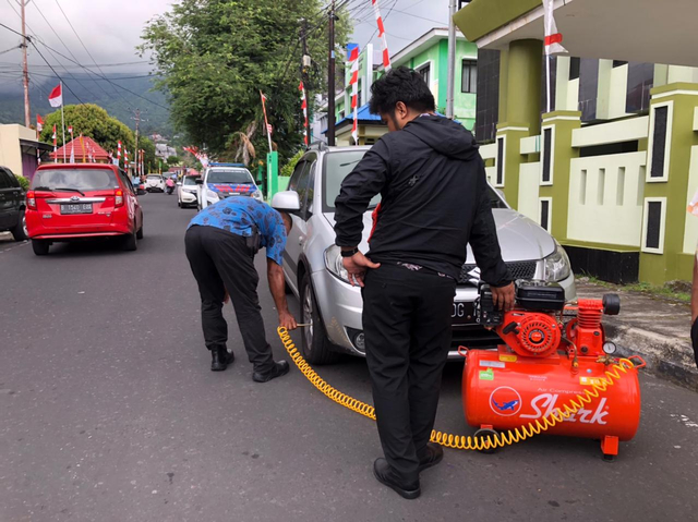 Polantas Polres Ternate saat mengempiskan ban mobil milik anggota DPRD. Foto: Samsul Hi Laijou/cermat