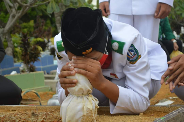 Putri Nur Azhima, mencium nisan di pusara sang ayah. Foto: Istimewa
