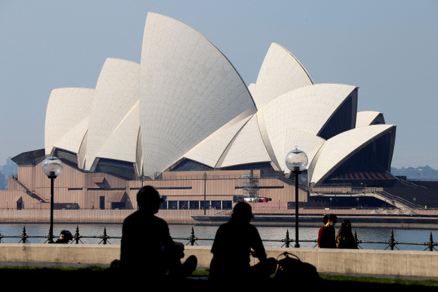 Pengunjung menghabiskan sore mereka di depan Sydney Opera House, Australia, saat pandemi COVID-19, Sabtu (21/8/2021). Foto: David Grey/AFP