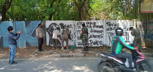 Petugas Satpol PP menghapus mural 'Tuhan Aku Lapar' di Jalan Raya Citayam, Pancoran Mas, Depok.  Foto: Dok. Istimewa
