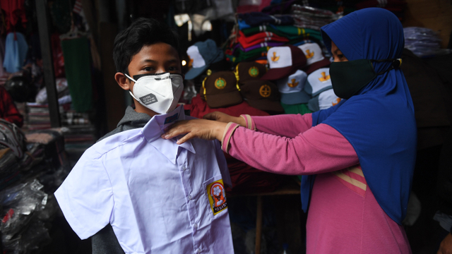 Warga mencoba seragam sekolah di Pasar Jatinegara, Jakarta, Minggu (29/8/2021). Foto: Akbar Nugroho Gumay/ANTARA FOTO
