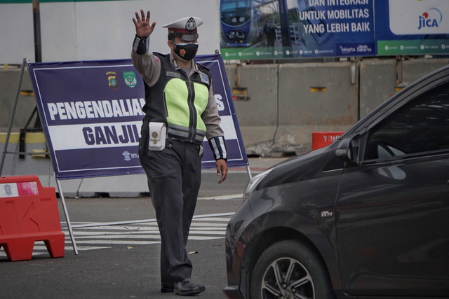 Polisi mengarahkan mobil ber-plat akhir angka genap pada titik ganjil-genap M.H Thamrin di Bundaran Patung Kuda dekat Monas, Rabu (1/9/2021). Foto: Jamal Ramadhan/kumparan