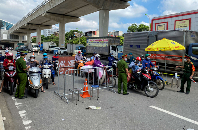 Petugas kepolisian Vietnam memeriksa dokumen perjalanan resmi pengendara di pos pemeriksaan pada hari pertama perpanjangan lockdown di Hanoi, Vietnam, Senin (6/9/2021). Foto: Stringer/Reuters