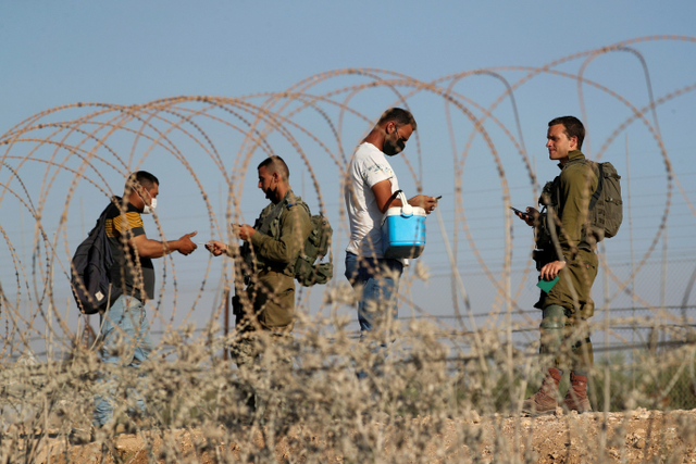 Tentara Israel memeriksa dokumen warga Palestina saat mereka menyeberang kembali ke Tepi Barat dari Israel melalui desa Muqeibila, Senin (6/9). Foto: Ammar Awad/Reuters