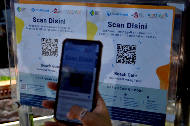 Pengunjung memindai QR Code dengan aplikasi PeduliLindungi saat hari pertama pembukaan mal di Beachwalk Shopping Center, Kuta, Badung, Bali, Rabu (8/9/2021). Foto: Fikri Yusuf/Antara Foto