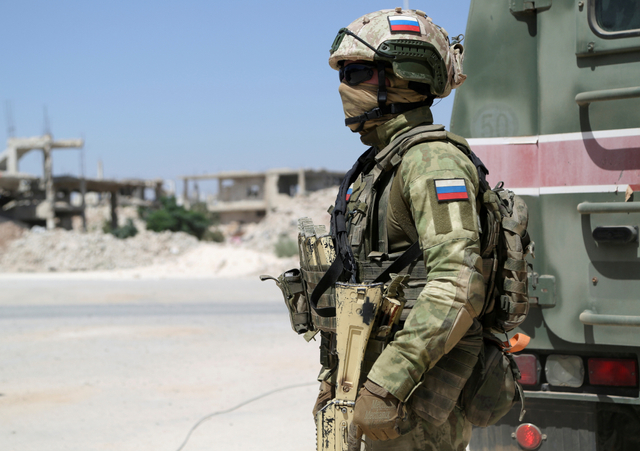Seorang perwira polisi militer Rusia berdiri di dekat bangunan yang rusak di Deraa al Balaad, Suriah, Kamis (9/9). Foto: Yamam al Shaar/REUTERS