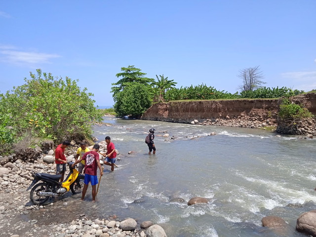 Masyarakat Manggarai Timur saat memikul motor melintasi Kali Wae Musur. Foto : Engkos Pahing