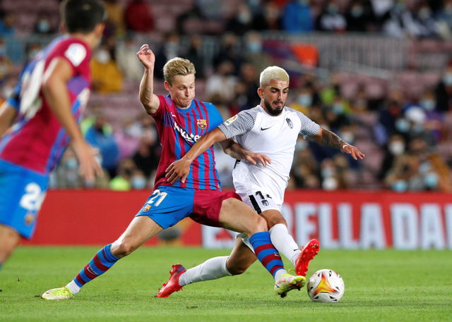 Pemain FC Barcelona Frankie de Jong duel dengan pemain Granada Monchu di Camp Nou, Barcelona, Spanyol. Foto: Albert Gea/Reuters