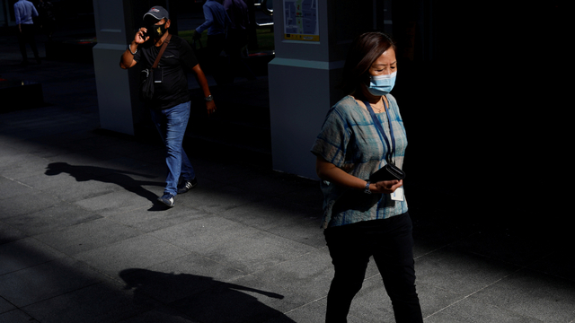 Pekerja kantor terlihat di kawasan pusat bisnis Singapura yang sebagian besar kosong akibat melonjaknya kasus COVID-19. Foto: Edgar Su/Reuters