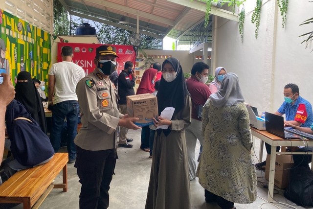 Penyerahan bingkisan kepada penerima vaksin COVID-19 pada vaksinasi yang digelar Polda Aceh bekerja sama Polresta Banda Aceh dan IDI Aceh di salah satu warung kopi kawasan Ulee Kareng. Foto: Dok. Humas Polda Aceh