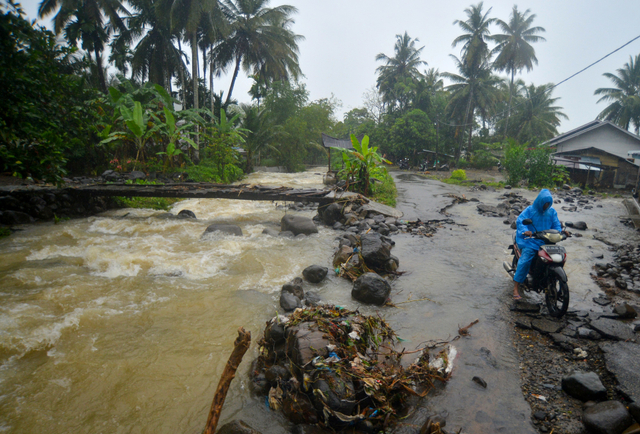 Warga melintasi jalan yang rusak usai diterjang banjir bandang di Kuliek, Nagari Sungai Buluah Timur, Kabupaten Padang Pariaman, Sumatera Barat, Kamis (30/9/2021). Foto: Iggoy el Fitra/Antara Foto
