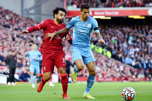 Pemain Liverpool Mohamed Salah berebut bola dengan pemain Manchester City Joao Cancelo pada pertandingan lanjutan Liga Inggris di Anfield, Liverpool, Inggris. Foto: Peter Powell/REUTERS