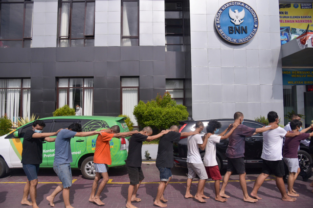 Petugas menggiring mahasiswa yang diamankan saat ungkap kasus di Kantor Badan Narkotika Nasional (BNNP) Provinsi Sumatera Utara, Percut Sei Tuan, Deliserdang, Sumatera Utara, Senin (11/10/2021). Foto: Fransisco Carolio/Antara Foto