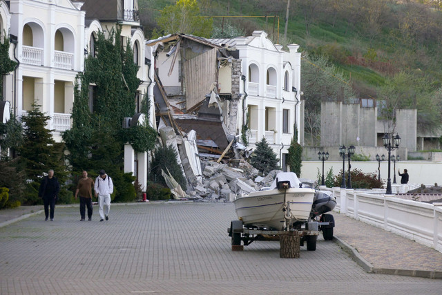 Orang-orang berjalan di depan hotel yang dihancurkan oleh rudal Rusia di Odesa, Ukraina, Minggu (8/5/2022). Foto: Igor Tkachenko/Reuters