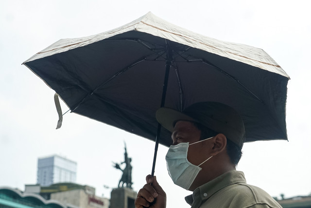 Seorang warga menggunakan payung guna terhindar dari panasnya matahari di Jakarta, pada Selasa (10/5/2022). Foto: Iqbal Firdaus/kumparan