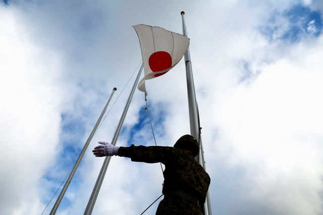 Anggota Pasukan Darat Bela Diri Jepang (JGSDF) mengibarkan bendera di Pulau Miyako, Okinawa, Jepang, Kamis (21/4/2022). Foto: Issei Kato/REUTERS