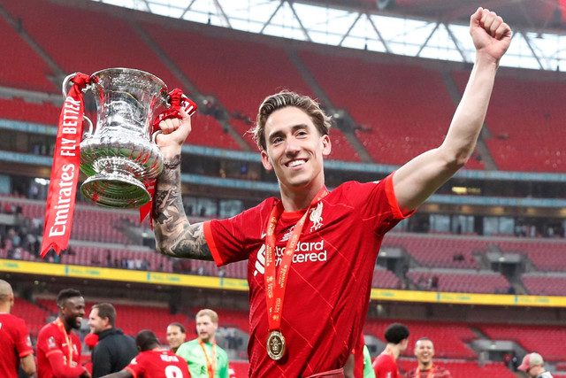 Pemain Liverpool Kostas Tsimikas mengangkat trofi setelah memenangkan final Piala FA di Stadion Wembley, London, Inggris, Sabtu (14/5/2022). Foto: Action Images via Reuters/Peter Cziborra