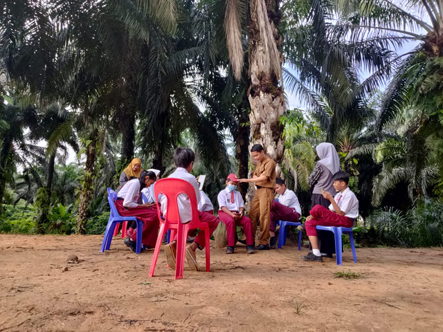 Para siswa yang sedang mengikuti kelas secara online melalui aplikasi rumah belajar, difasilitasi oleh guru, di lokasi yang terdapat sinyal internet. Sumber: Koleksi CLC Luang Manis, Kalabakan, Sabah, Malaysia.