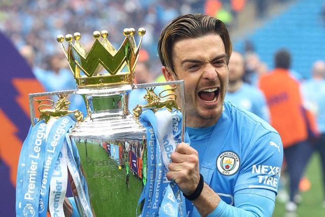 Pemain Manchester City Jack Grealish merayakan dengan trofi setelah memenangkan Liga Premier di Stadion Etihad, Manchester, Inggris, Minggu (22/5/2022). Foto: Hannah McKay/REUTERS