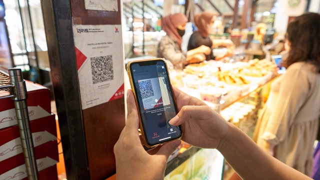 Seorang pembeli saat bertransaksi menggunakan aplikasi QRIS. (foto: dok istimewa)