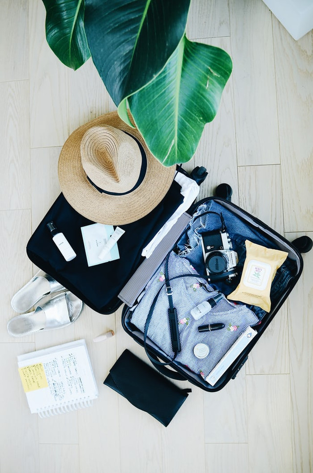 cara melipat baju untuk traveling. sumber foto : Unsplash/Topi cokelat dan koper.