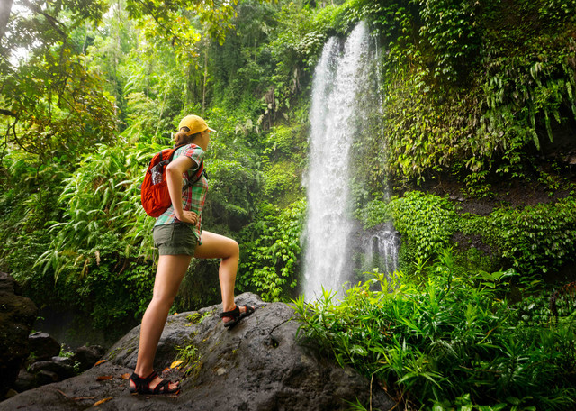Ilustrasi wanita yang sedang hiking sambil menatap indahnya air terjun. Foto: soft_light/Shutterstock