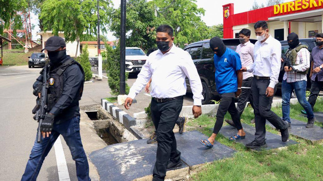 AB alias TW (baju biru) yang diduga sebagai aktor intelektual penembakan dua warga Aceh Besar dibawa untuk dihadirkan pada rilis kasus di Mapolda Aceh, Senin (6/6/2022). Foto: Suparta/acehkini