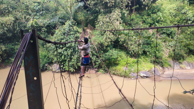 Warga Desa Salamnunggal, Kecamatan Cibeber dan Desa Sukarama, Kecamatan Bojongpicung, Kabupaten Cianjur, Jawa Barat, melewati jembatan rusak. Foto: Dok. Istimewa