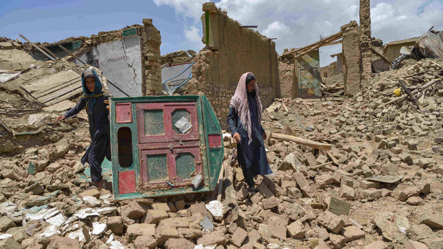 Warga menemukan barang yang bisa mereka selamatkan di reruntuhan rumah yang rusak akibat gempa bumi di distrik Bermal, provinsi Paktika, Kamis (23/6/2022). Foto: Ahmad SAHEL ARMAN/AFP