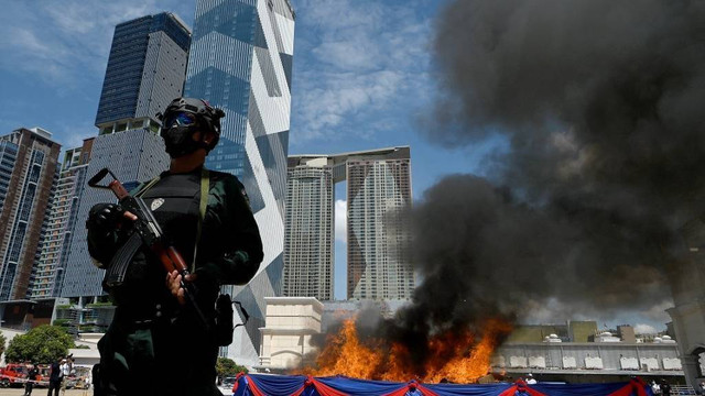 Polisi berjaga di dekat tumpukan obat terlarang yang disita selama upacara penghancuran untuk menandai "Hari Internasional Melawan Penyalahgunaan Narkoba dan Perdagangan Gelap" PBB di Phnom Penh, Kamboja pada Minggu (26/6/2022). Foto: Tang Chhin Sothy/AFP