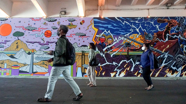 Sejumlah warga berjalan kaki melintasi mural di terowongan Stasiun Sudirman atau yang biasa dikenal dengan Terowongan Kendal di Jakarta, Selasa (5/7/2022). Foto: Iqbal Firdaus/kumparan