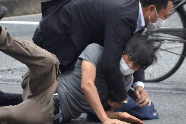 Seorang pria, diyakini sebagai tersangka penembakan mantan Perdana Menteri Jepang Shinzo Abe ditahan oleh petugas polisi di Stasiun Yamato Saidaiji di Nara, Prefektur Nara, Jepang, Jumat (8/7/2022). Foto: Kyodo/via REUTERS