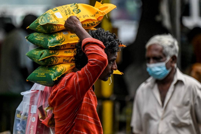 Pekerja mengangkut biji-bijian makanan dan barang-barang penting lainnya di Kolombo, Sri Lanka pada Kamis (12/5/2022). Foto: Ishara S. Kodikara/AFP