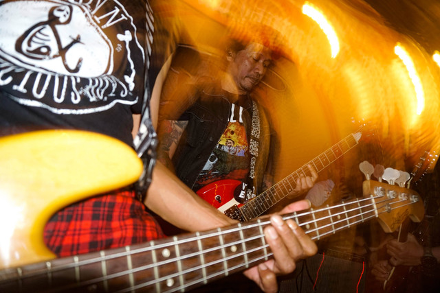 Buluk memainkan gitar saat tampil bersama Glenn and Vicious Boys, grup musik yang ia produseri, pada Minggu (20/3/2022). Saat ia kembali ke skena musik sebelum menghilang, Buluk aktif memproduseri beberapa grup musik punk. Foto: Iqbal Firdaus/kumparan