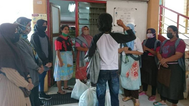 Berkah Hamulya, kaos putih lengan reglan hitam, bersama sejumlah relawan sedang menyiapkan makan siang untuk para buruh gendong. Foto: Widi Erha Pradana.