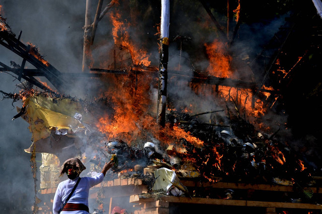 Warga menyaksikan prosesi kremasi saat upacara Ngaben massal di Desa Adat Padangbai, Karangasem, Bali, Jumat (29/7/2022). Foto: Fikri Yusuf/ANTARA FOTO