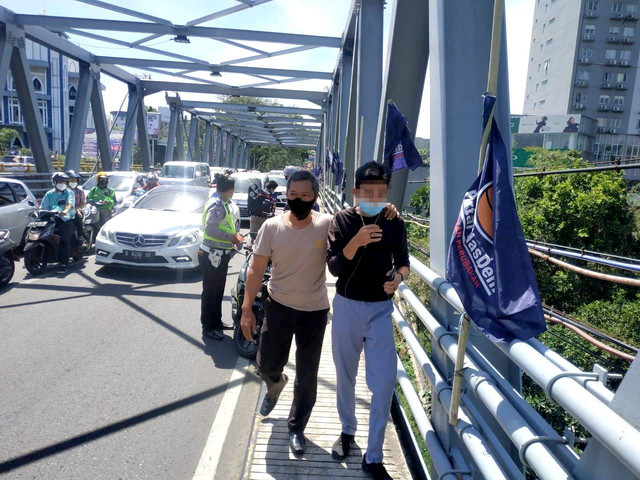 Petugas mengamankan pelajar yang melakukan aksi percobaan bunuh diri di Jembatan Suhat, Kota Malang. foto/Humas Polresta Malang Kota