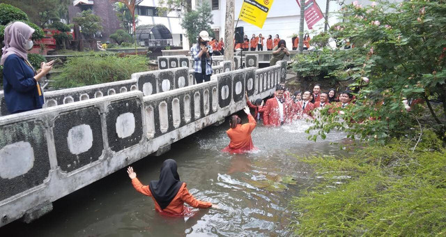 Keseruan jeguran di dalam kolam sarjana diikuti mahasiswa yang dinyatakan lulus dalam sidang akhir skripsi. Foto / Feni Yusnia