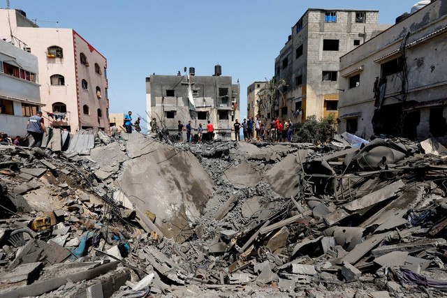 Warga Palestina memeriksa bangunan yang terkena serangan udara Israel, di Kota Gaza, Sabtu (6/8/2022). Foto: Mohammed Salem/REUTERS