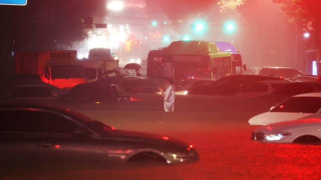 Seorang pria berdiri di antara kendaraan yang ditinggalkan di daerah banjir saat hujan lebat di Seoul, Korea Selatan, Senin (8/8/2022). Foto: Yonhap via REUTERS