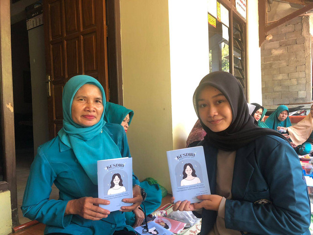 Mahasiswa KKN bersama dengan Ibu ketua RW 01 Kelurahan Cepoko memegang buku panduan KESDIRI (Sumber : Foto Pribadi)