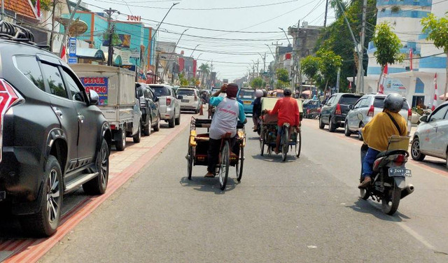 Sejumlah mobil parkir di bahu jalan dan kendaraan lain lewat berlawanan arah. (setyadi/panturapost.com)