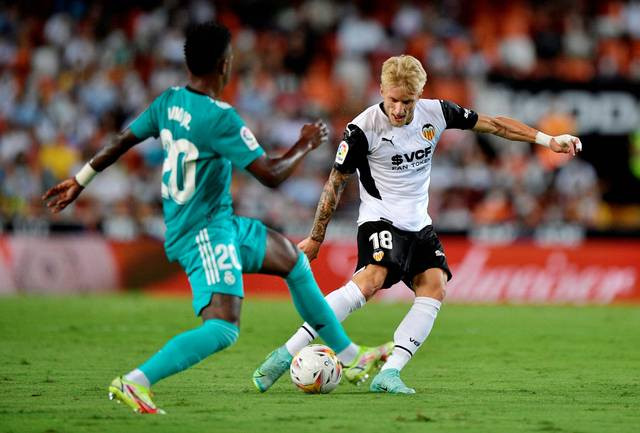 Pemain Valencia Daniel Wass berusaha melewati pemain Real Madrid saat pertandingan di Mestalla, Valencia, Spanyol. Foto: Pablo Morano/Reuters